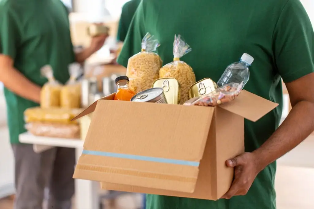 image of a volunteer with a food box giving it to someone who was displaced after a disaster. It is used in an article by Ministries of Grace about how Monthly giving helps provide relief for people effected by a disaster in Georgia.