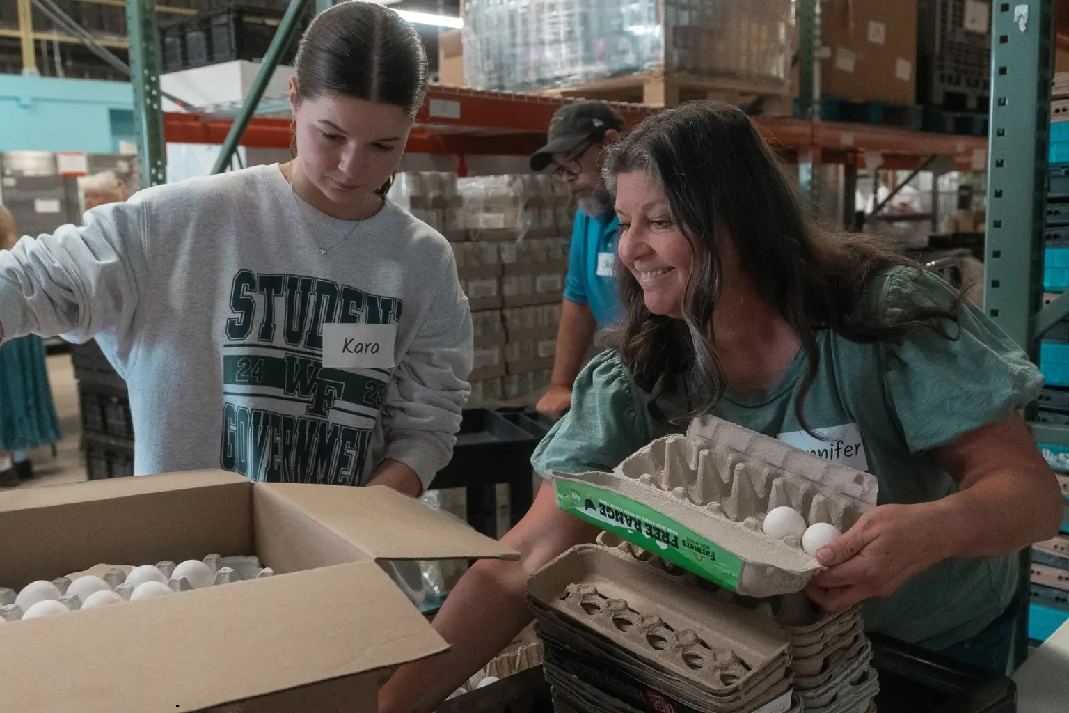 Image of two Ministries of Grace Volunteers helping pack a food box for disaster relief survivors. The image is used to represent how Monthly giving can support disaster relief victims in Georgia.