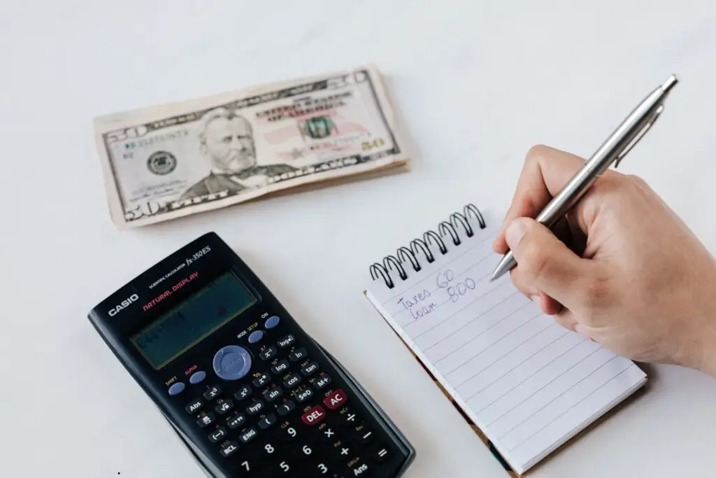 image of someone doing their budget with a calculator and some cash also on the table. It is to represent how monthly giving can help support the financial stability of families in Georgia.